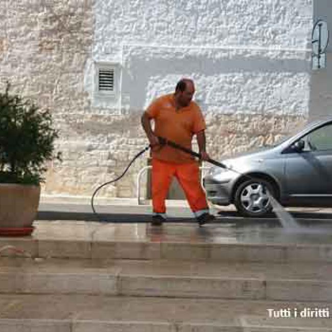 uomo che pulisce strada con idropulitrice